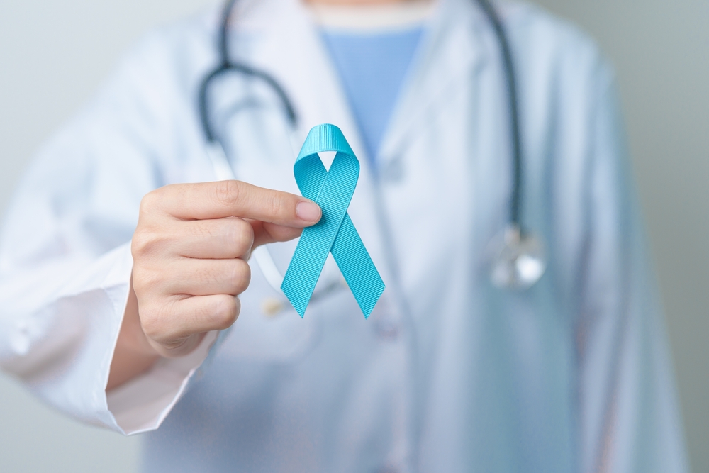 doctor holding light blue ribbon.